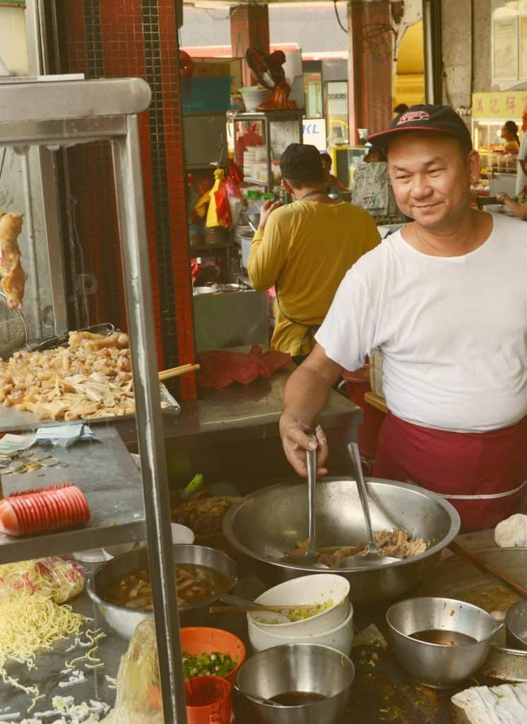Traditional Malaysian street food being prepared over a charcoal fire