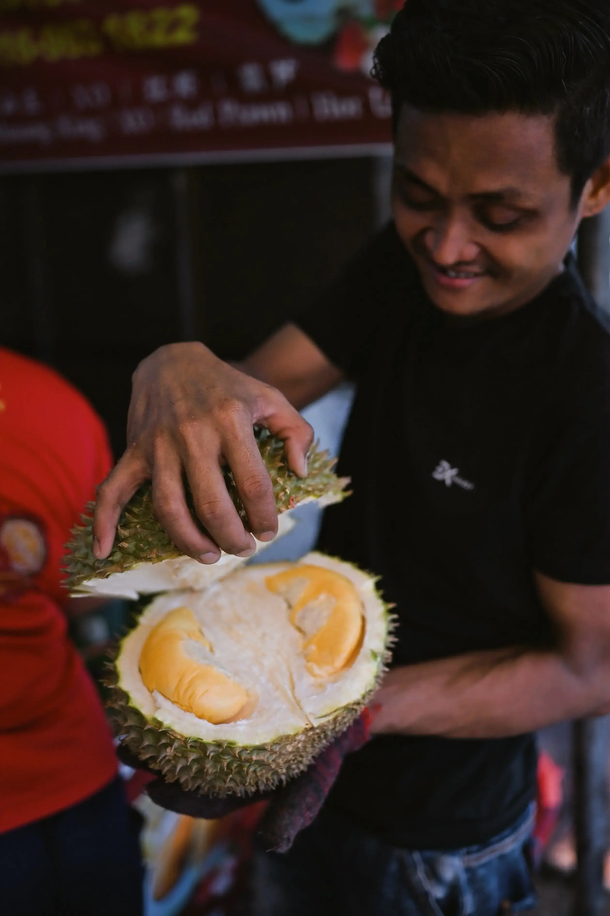 Vendor holding a durian fruit in a market stall in Penang